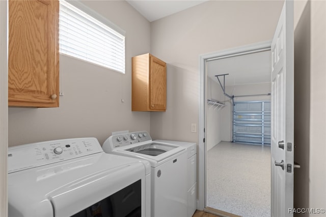 clothes washing area with washing machine and dryer and cabinets