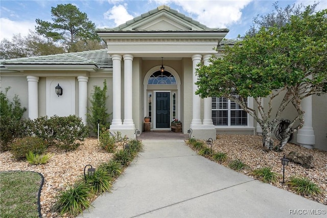 doorway to property featuring a tile roof and stucco siding