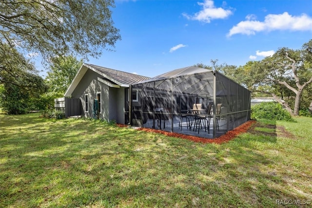 rear view of house with a lawn, a patio, and glass enclosure