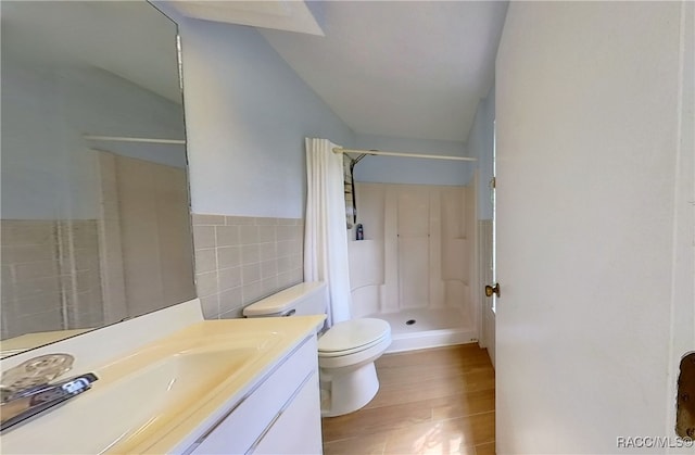 bathroom featuring hardwood / wood-style flooring, tile walls, vanity, a shower, and toilet