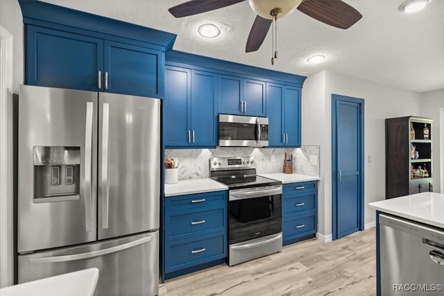 kitchen featuring blue cabinetry, ceiling fan, stainless steel appliances, tasteful backsplash, and light wood-type flooring