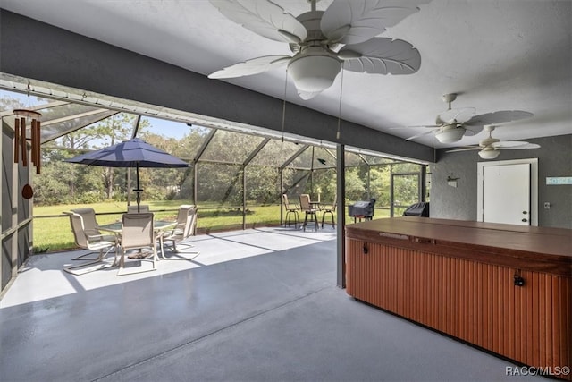 view of patio / terrace featuring ceiling fan, a hot tub, and glass enclosure