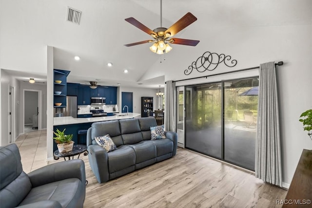 living room featuring high vaulted ceiling, sink, ceiling fan with notable chandelier, and light hardwood / wood-style floors