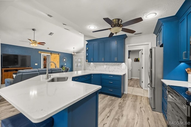 kitchen with stainless steel refrigerator, sink, a kitchen bar, kitchen peninsula, and a barn door