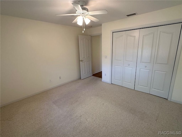 unfurnished bedroom featuring light colored carpet, a closet, and ceiling fan