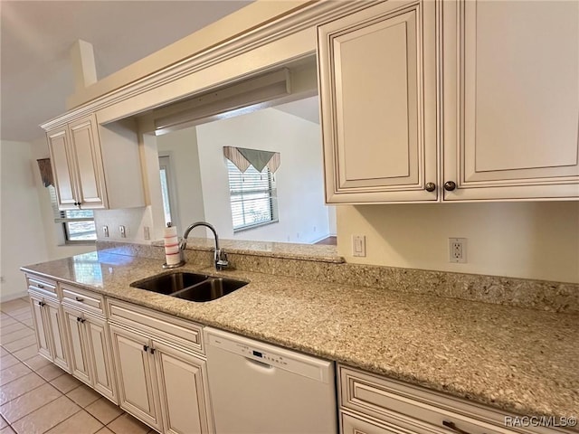 kitchen with sink, light tile patterned floors, dishwasher, light stone counters, and cream cabinets