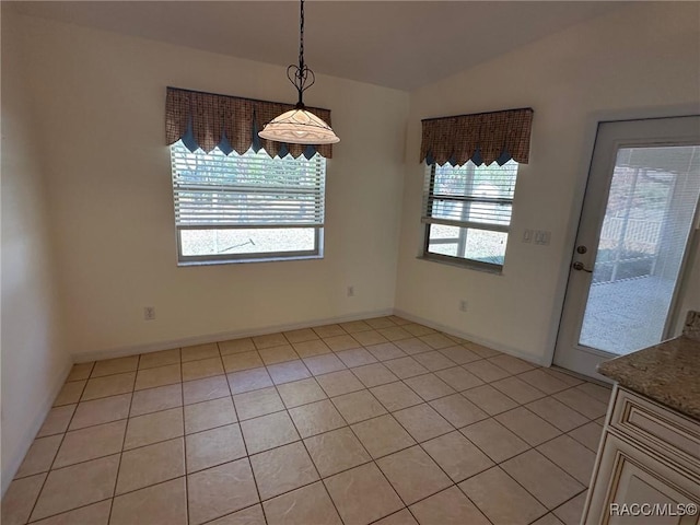 unfurnished dining area with lofted ceiling and light tile patterned floors