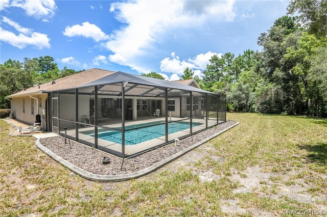 view of pool with glass enclosure, a yard, and a patio