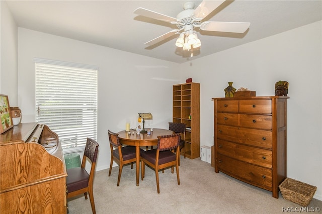 dining space with ceiling fan and light colored carpet