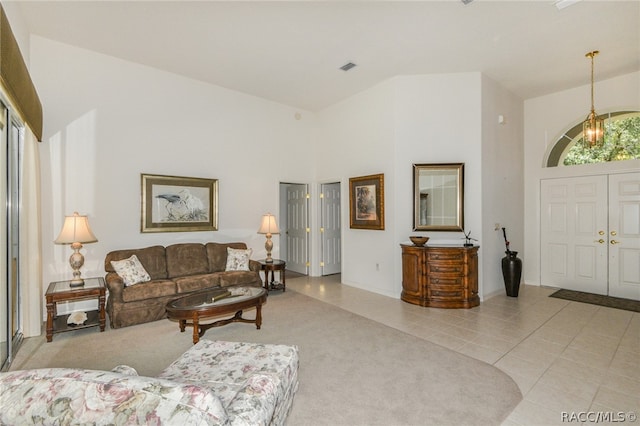 living room featuring light tile patterned floors, a towering ceiling, and an inviting chandelier