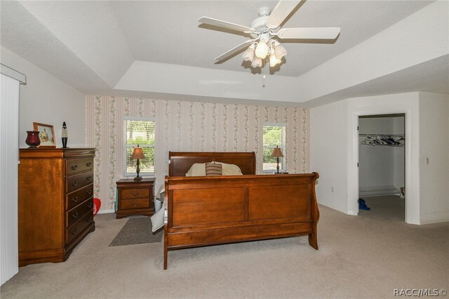 bedroom featuring ceiling fan, light carpet, a tray ceiling, and multiple windows