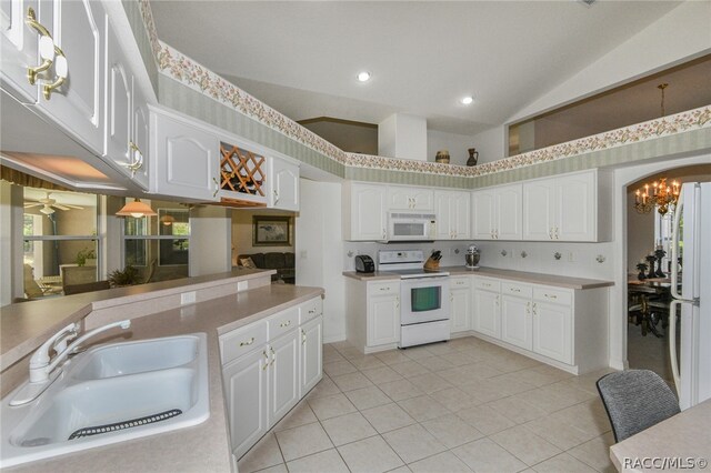 kitchen featuring white appliances, ceiling fan with notable chandelier, sink, light tile patterned floors, and white cabinetry