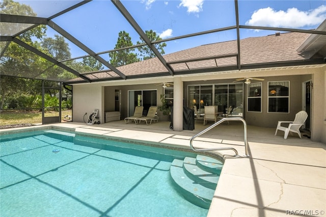 view of pool featuring a patio, glass enclosure, and ceiling fan