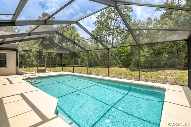 view of pool with a patio, glass enclosure, and a lawn