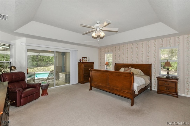 bedroom featuring access to exterior, a tray ceiling, ceiling fan, and light colored carpet