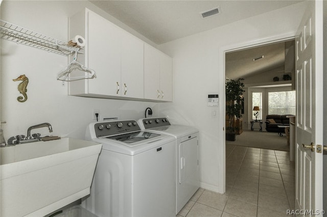 laundry area with light tile patterned flooring, cabinets, independent washer and dryer, and sink