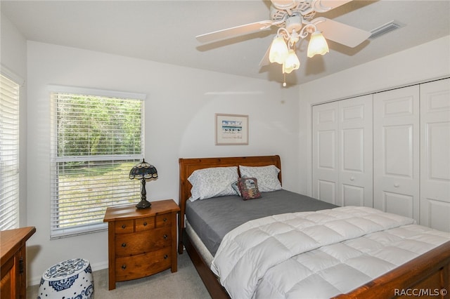 carpeted bedroom with multiple windows, ceiling fan, and a closet