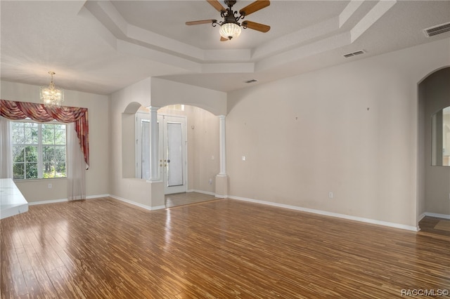 spare room with a tray ceiling, wood-type flooring, and ceiling fan with notable chandelier