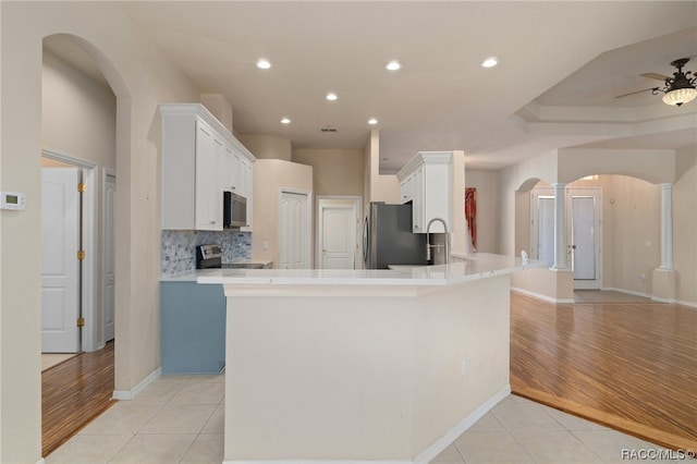 kitchen with kitchen peninsula, light hardwood / wood-style flooring, white cabinets, and appliances with stainless steel finishes