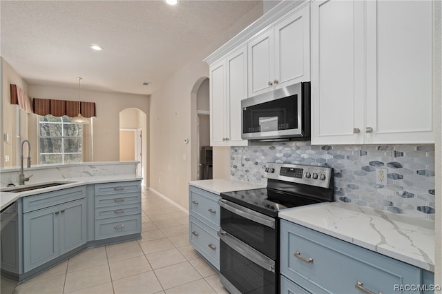 kitchen with sink, decorative backsplash, decorative light fixtures, white cabinetry, and stainless steel appliances