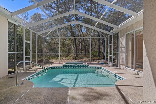 view of pool featuring glass enclosure, an in ground hot tub, and a patio area