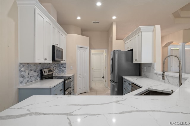 kitchen with light stone countertops, tasteful backsplash, stainless steel appliances, sink, and white cabinets