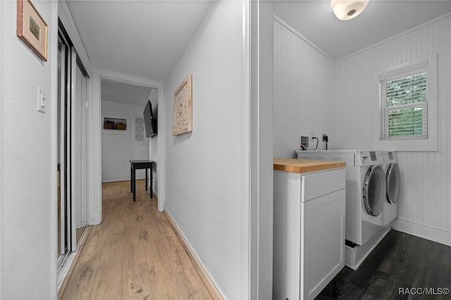 laundry area featuring light wood-style floors, baseboards, cabinet space, and independent washer and dryer