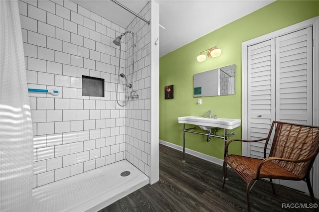 full bathroom featuring tiled shower, a sink, baseboards, and wood finished floors