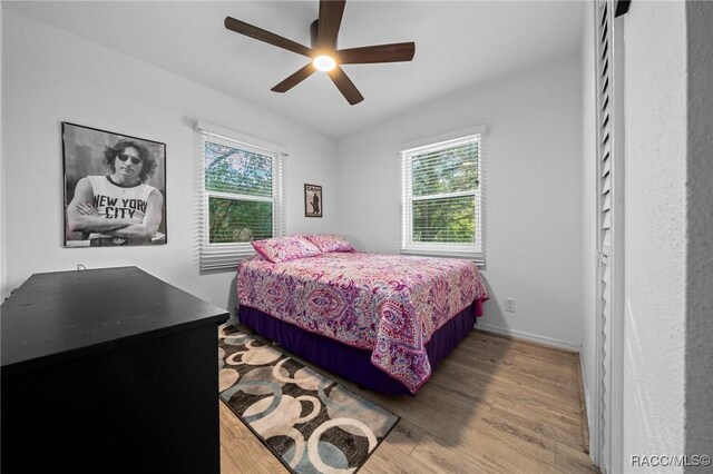 bedroom with baseboards, multiple windows, a ceiling fan, and wood finished floors