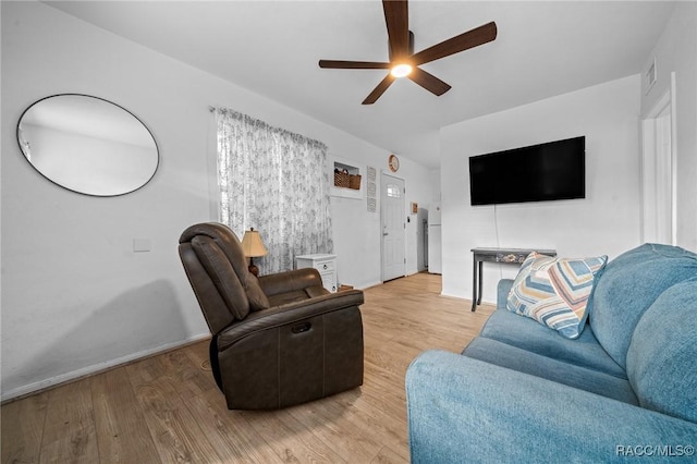 living room with baseboards, visible vents, ceiling fan, and light wood finished floors