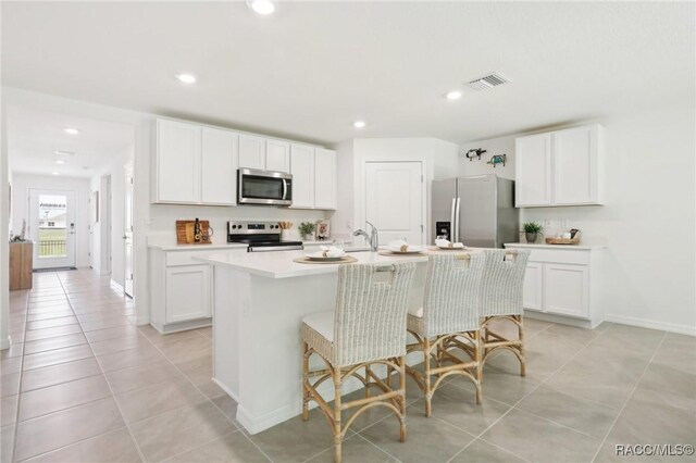 3342 W Crandon Dr, Dunnellon, FL 34433 - kitchen with appliances with stainless steel finishes, an island with sink, light tile patterned floors, light countertops, and white cabinetry