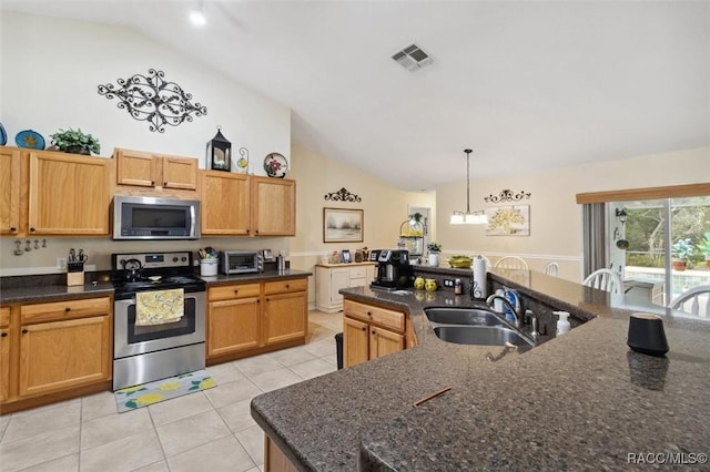 kitchen with appliances with stainless steel finishes, pendant lighting, sink, dark stone countertops, and light tile patterned floors