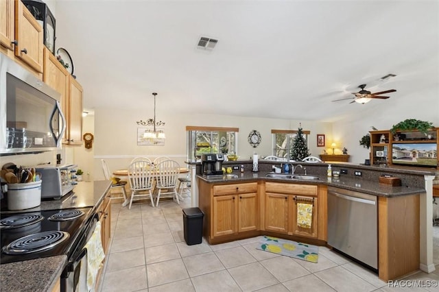 kitchen featuring ceiling fan with notable chandelier, pendant lighting, sink, dark stone countertops, and stainless steel appliances