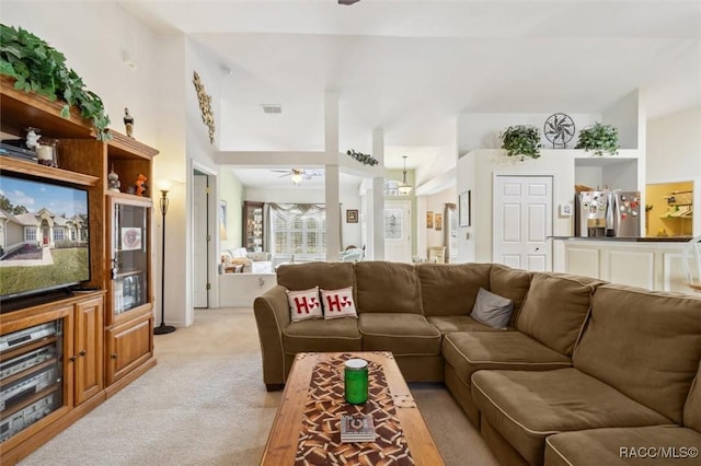 living room featuring ceiling fan, light carpet, and vaulted ceiling