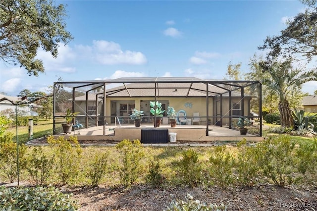 rear view of property with glass enclosure, a patio area, and a pool