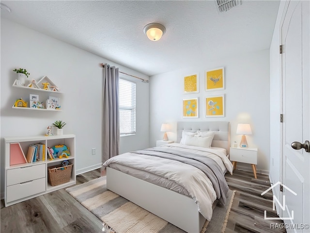 bedroom featuring a textured ceiling and dark hardwood / wood-style flooring