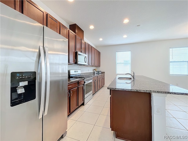 kitchen featuring sink, stainless steel appliances, a textured ceiling, a kitchen island with sink, and light tile patterned floors