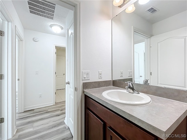 bathroom featuring hardwood / wood-style floors, vanity, and a textured ceiling