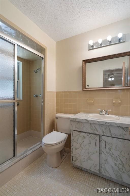 6580 E Glencoe St, Inverness, FL 34452 - bathroom with vanity, a shower stall, toilet, tile walls, and a textured ceiling