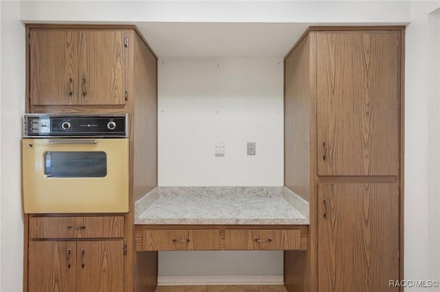 6580 E Glencoe St, Inverness, FL 34452 - kitchen with oven, brown cabinets, light countertops, and a desk