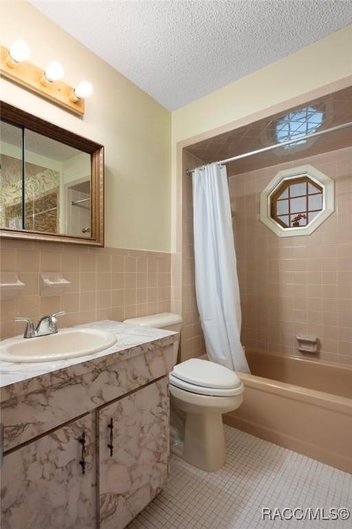 6580 E Glencoe St, Inverness, FL 34452 - bathroom with tile walls, tile patterned floors, vanity, toilet, and shower / bath combination with curtain