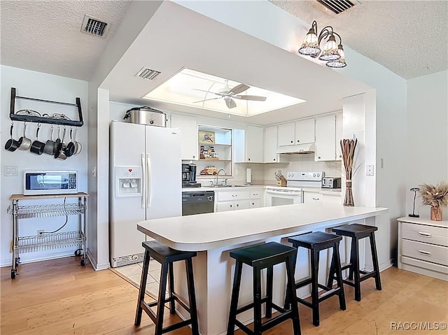 2582 W Fairway Loop, Citrus Springs, FL 34434 - kitchen with white appliances, a textured ceiling, light wood-style flooring, a peninsula, and a ceiling fan