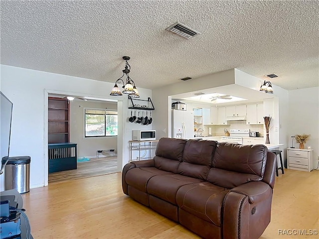 2582 W Fairway Loop, Citrus Springs, FL 34434 - living area with a textured ceiling, light wood-style floors, and a chandelier