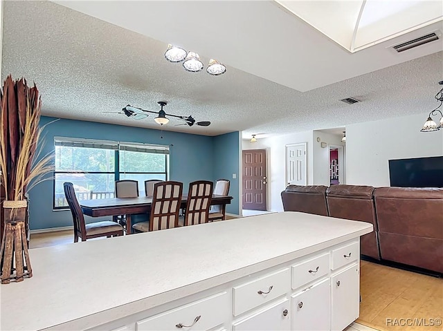 2582 W Fairway Loop, Citrus Springs, FL 34434 - kitchen with light countertops, a textured ceiling, light wood-style floors, white cabinetry, and open floor plan