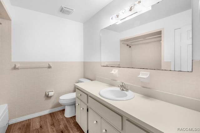 bathroom featuring toilet, vanity, tile walls, and hardwood / wood-style flooring