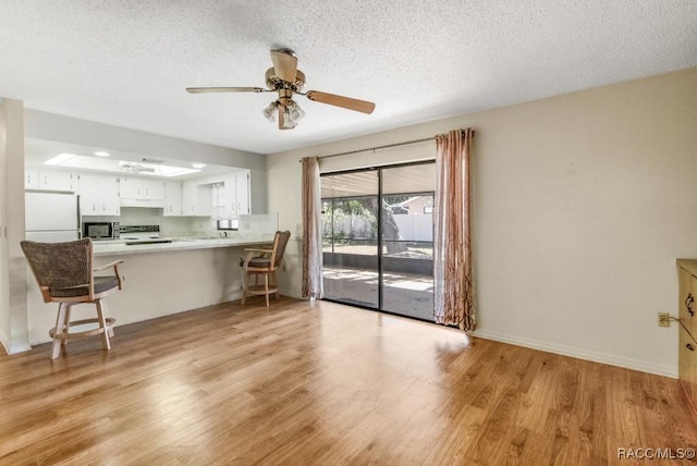 kitchen with kitchen peninsula, white cabinetry, stainless steel appliances, and light hardwood / wood-style floors