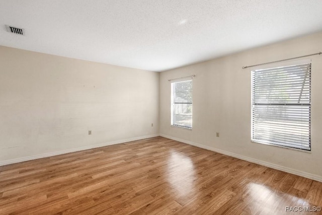 spare room featuring light hardwood / wood-style floors and a textured ceiling