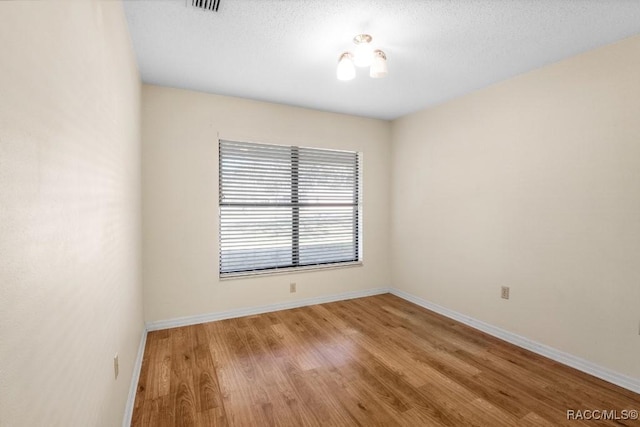 unfurnished room with a textured ceiling and hardwood / wood-style flooring