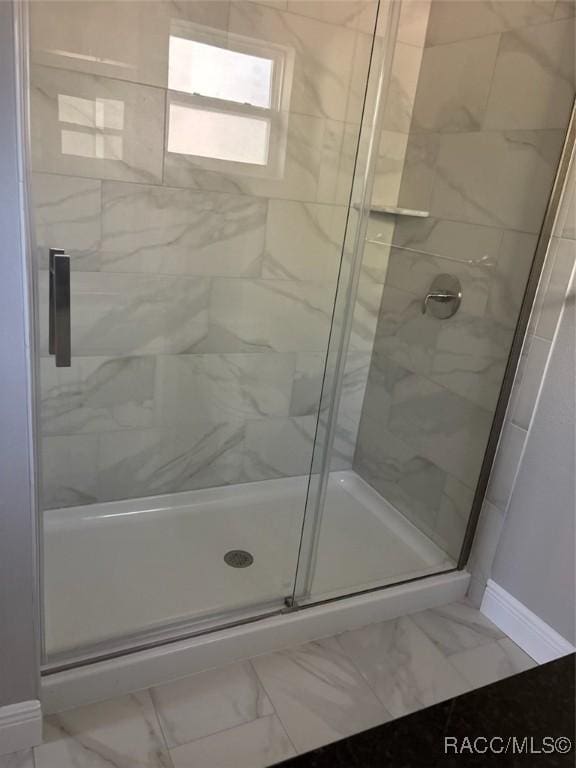 bathroom featuring a shower stall, baseboards, and marble finish floor