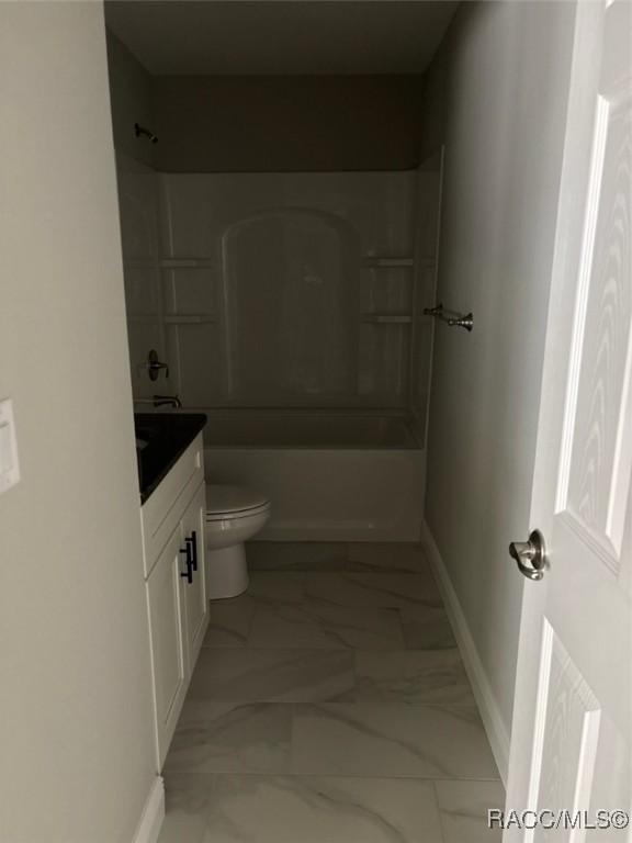 bathroom with toilet, marble finish floor, washtub / shower combination, baseboards, and vanity